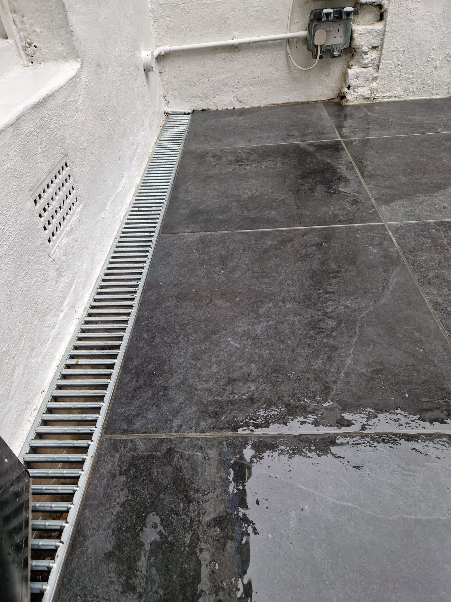 Dark tiled patio with drainage channel